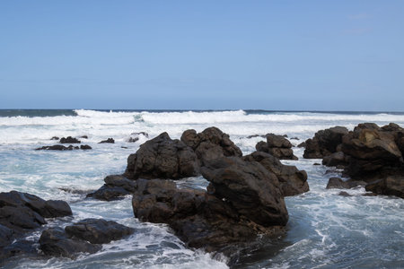 Big volcanic black rocks on the coast of Atlantic ocean with intense waves during winter windy day....