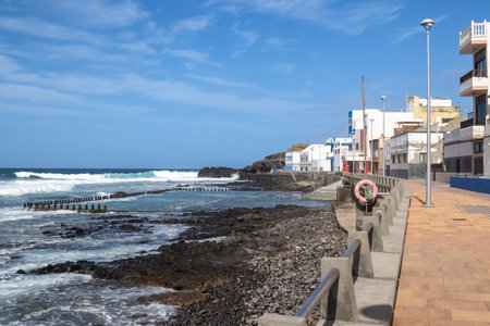 Calm day on a promade by Atlantic ocean. Colorful houses. Rocky beach. Blue sky with white clouds....