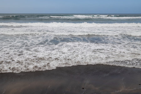 Coast with waves  and foam on the sandy beach of Atlantic ocean.  Blue sky. Las Palmas de Gran...