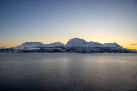 Nature with snow in the arctic sunset in the late autumn. Calm water of Norwegian sea. Clear...