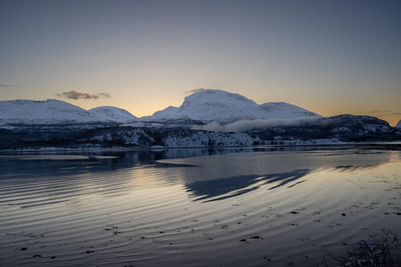 Nature with snow in the arctic sunset in the late autumn. Calm water of Norwegian sea. Clear...