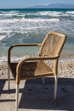 Terrace of a restaurant on the coast of Ionian sea, above the beach. Empty during siesta time. Comfortable chair with a seaview. Intense waves. Sunny day. Acharavi, Corfu (Korfu), Greece.の写真素材