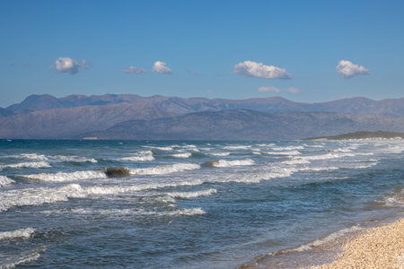 Ionian sea with dramatic waves during a late summer day. Albanian mountains in the background. Blue sky with white clouds. North of the island Corfu (Korfu), Acharavi, Greece.の写真素材