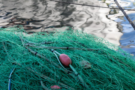 Pile of green fishing nets with red buoys on the coast of Ionian sea. Water with reflections in the background. Kalami, Kouloura, Corfu (Korfu), Greece.の写真素材