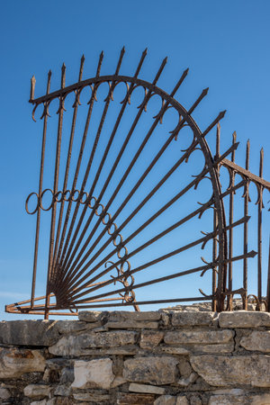 Stone fence with metal part on the top. Arrows pointing to the right and to the top. Bright blue sky. Koulora, Kalami, Corfu (Korfu), Greece.の写真素材