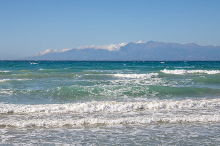 Ionian sea with dramatic waves during a late summer day. Albanian mountains in the background. Blue sky with white clouds. North of the island Corfu (Korfu), Acharavi, Greece.の写真素材
