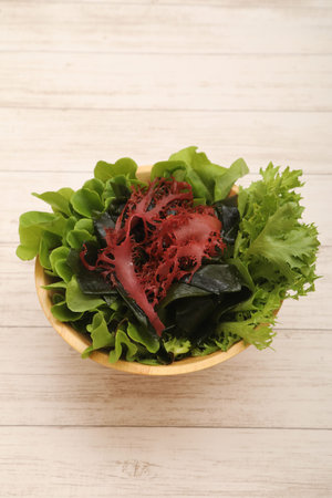 Bowl of fresh salad with seaweed on wooden background, top viewの写真素材