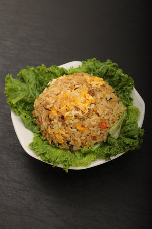 Fried rice with meat and vegetables in a plate on black backgroundの写真素材