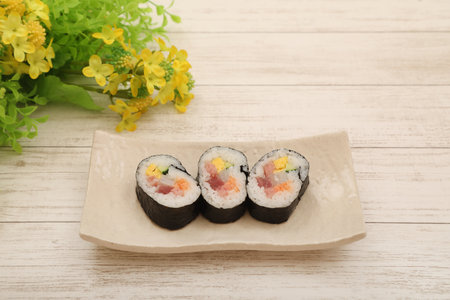 Sushi rolls on a plate with yellow flowers on a white wooden backgroundの写真素材