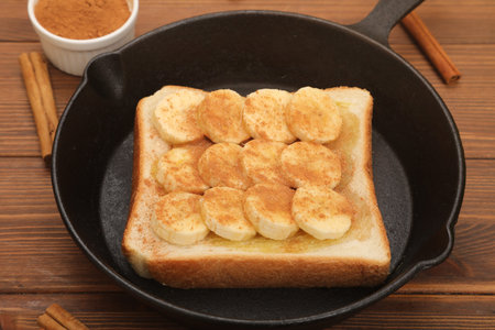 Toast with bananas and cinnamon in a pan on a wooden backgroundの写真素材