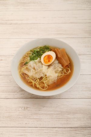 Soy sauce flavored Japanese wonton noodles with egg and bamboo shoots
 on wood backgroundの写真素材