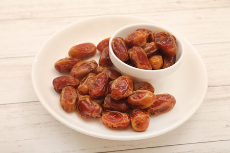 Dates fruit in a bowl on white wooden background. Top view.