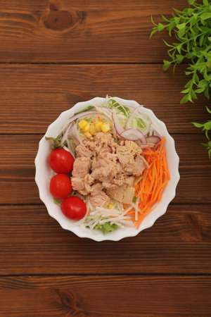 Tuna salad in a white bowl on wooden background, top viewの写真素材