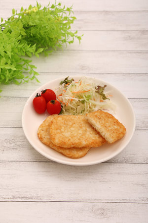 Hashed potatoes with salad and tomatoes on a white wooden background.