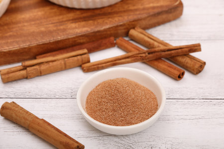 Bowl with cinnamon sugar and cinnamon sticks on wooden background, closeupの写真素材