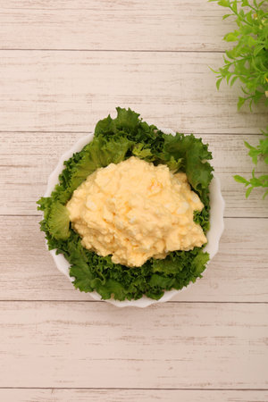 Tartar sauce and lettuce salad in a white bowl on a wooden background