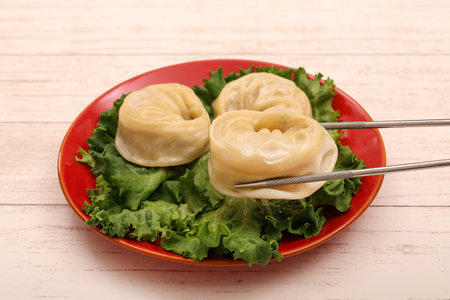 Korean-style  dumplings on plate with chopsticks over wooden backgroundの写真素材