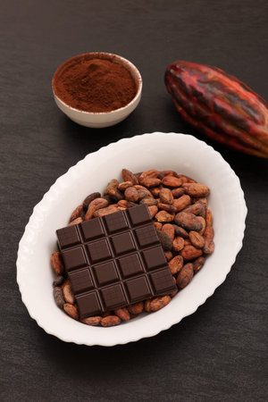 Cocoa beans, chocolate and cocoa powder on a black background