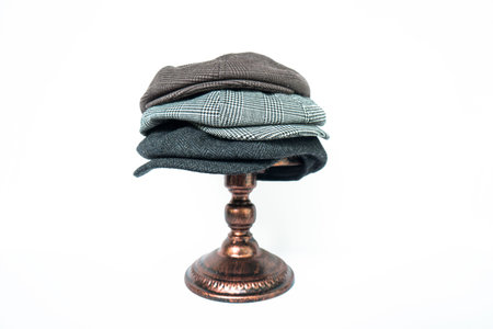 Stacks of classic hats like newsboy hats and flat hats in different colors and designs on a white...