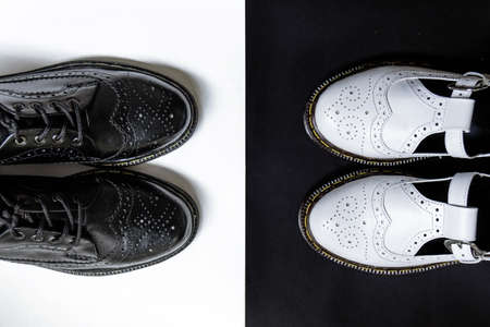 Detail of a pair of classic black and white brogue wingtip shoes for men and women on a black and white backgroundの写真素材