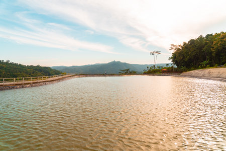 Reservoir on a vacant lot in countryside with view of wide hills and cloudy blue sky. as a natural water storage area when the dry season arrives, as well as a tourist locationの写真素材