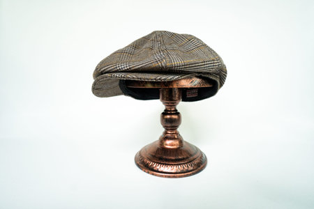 Detail of a classic eight-panel newsboy hat, in dark brown herringbone tweed fabric set against a...