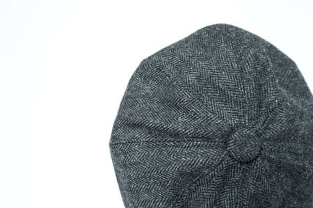 Detail of a classic eight-panel newsboy hat, in -black-dark color herringbone tweed fabric set against a bronze head mannequin on a white backgroundの写真素材