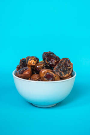 A small bowl of dates is served as a menu for breaking the fast with a Tosca background for the blessed month of Ramadanの写真素材