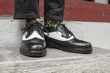 The young man wore a classic two-tone genuine leather brogue, vintage brogue wingtips that were shiny and ready to hang out on a sunny day.の写真素材