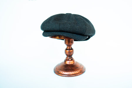 Photo of a classic hat catalog with an eight-panel newsboy cap in cozy woolen midnight black, mounted on a bronze mannequin head against a white studio backgroundの写真素材