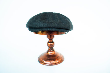 Photo of a classic hat catalog with an eight-panel newsboy cap in cozy woolen midnight black, mounted on a bronze mannequin head against a white studio backgroundの写真素材