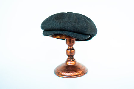 Photo of a classic hat catalog with an eight-panel newsboy cap in cozy woolen midnight black, mounted on a bronze mannequin head against a white studio backgroundの写真素材