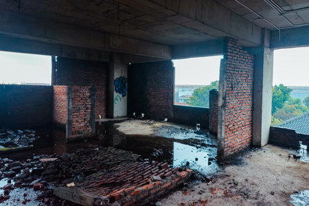 The inside of a former multi-storey building that was almost destroyed. An abandoned building with lots of puddles of rainwater, dirty and messyの写真素材