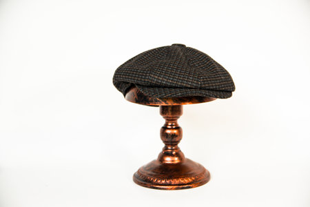 Detail of a newsboy hat made of wool fabric with a pattern mounted on a bronze mannequin head with a white background. Classic newsboy hat photo concept on a bronze mannequinの写真素材