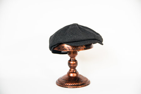 Detail of a black herringbone newsboy hat mounted on a bronze mannequin head on a white background. concept photo of a classic newsboy hat in jet black on a bronze mannequinの写真素材