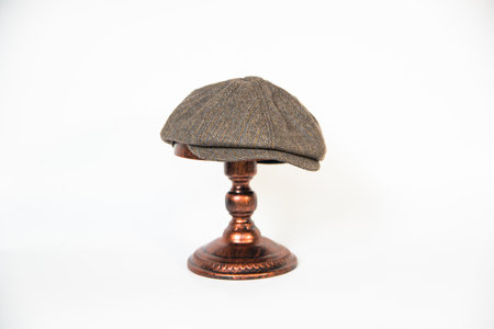Detail of a patterned herringbone newsboy hat mounted on a bronze mannequin head on a white background. concept photo of a classic khaki newsboy hat on a bronze mannequinの写真素材