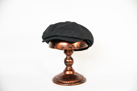Detail of a black herringbone newsboy hat mounted on a bronze mannequin head on a white background. concept photo of a classic newsboy hat in jet black on a bronze mannequinの写真素材