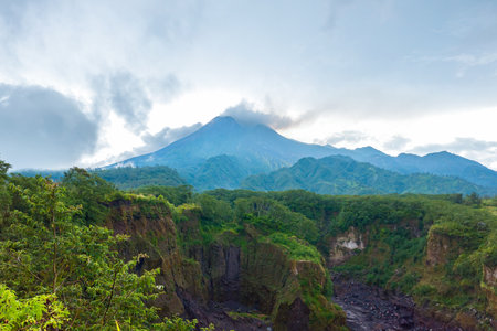 Panorama of Mount Merapi with rows of clouds around it in the afternoon. Landscape of active volcano in detail from south side with rocks and ravine in frontの写真素材