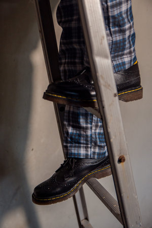 Close-up concept photo of lower body detail of man wearing solid black wingtip brogue shoes with...