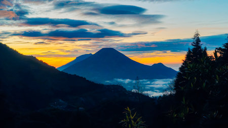 Landscape of Mount Sindoro seen from the peak of Mount Prau on a clear morning. Panorama of Mount Sindoro with the peak of Mount Prau in the foreground.の写真素材