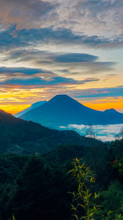 Landscape of Mount Sindoro seen from the peak of Mount Prau on a clear morning. Panorama of Mount Sindoro with the peak of Mount Prau in the foreground.の写真素材