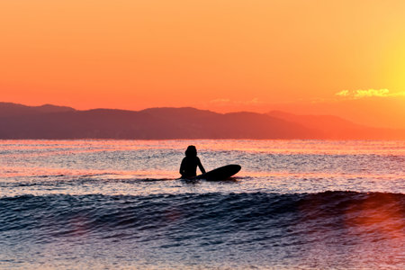 Surfer looking at the sunrise (silhouette)