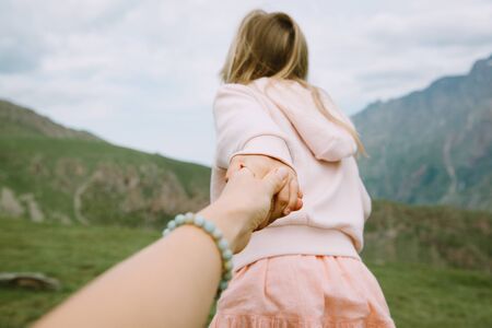 Little girl pulling adult's hand into the mountainsの写真素材