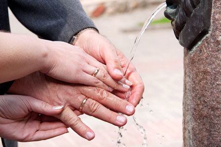 happy elderly couple washes his hands in the fountain