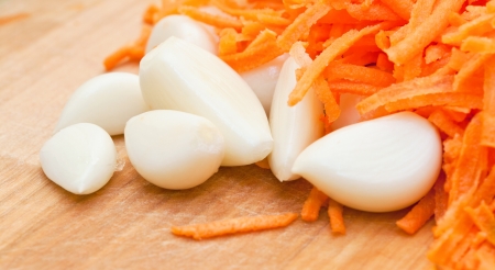 cloves of garlic and grated carrot on a plateの写真素材