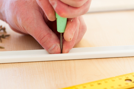 A man carries out the assembly of furniture, makes holes with an awlの写真素材