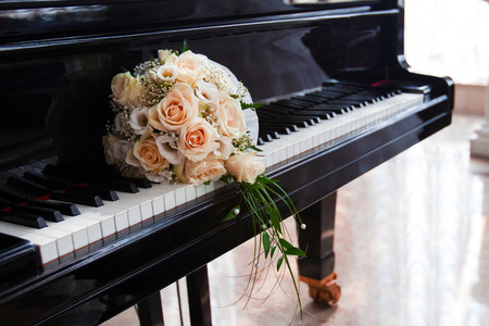 wedding bouquet of roses lies on the keys of the grand pianoの写真素材