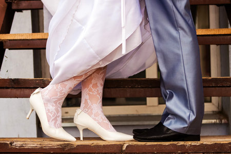wedding details: legs of the bride and groom on the wooden steps