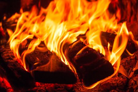 bright fire in the fireplace, in the foreground burned firewoodの写真素材