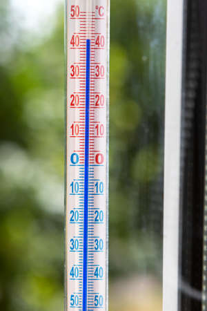 A Celsius thermometer on a window frame shows high temperatures of 43 degrees during an abnormal heat outside.の写真素材